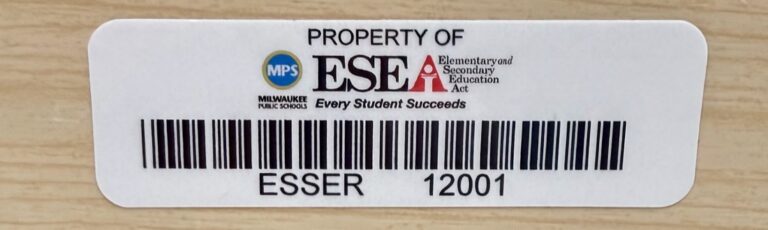 School property tag with district and ESEA logos, the words Every Student Succeeds, a barcode, and the number ESSER 12001